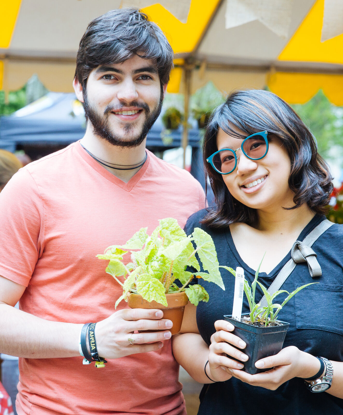 A man and woman both holding plants at a PHS plant sale.