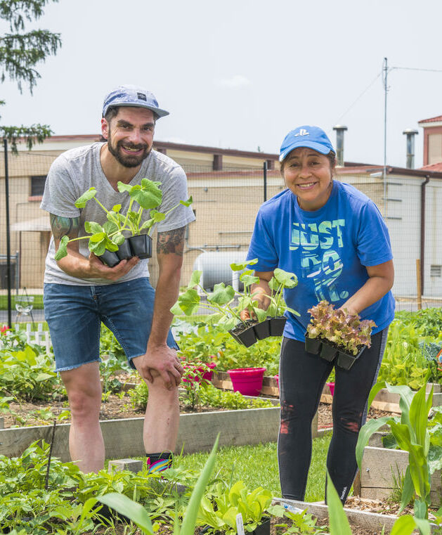 A man and a woman at the Fatima Community Garden holding produce