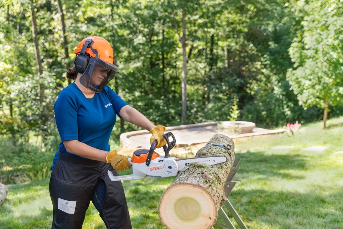 Woman using a chainsaw to cut lumber